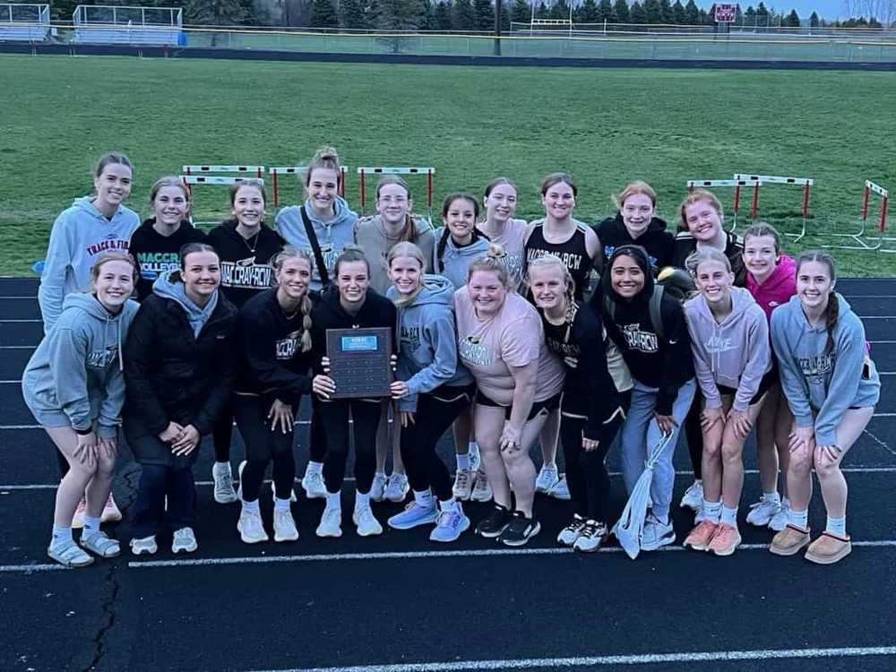 The girls’ track team celebrates together with their invitational trophy.